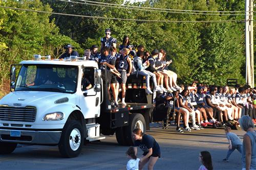 full football team pulled by large truck with flatbed